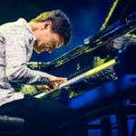 Mężczyzna w jasnej koszuli grający na fortepianie