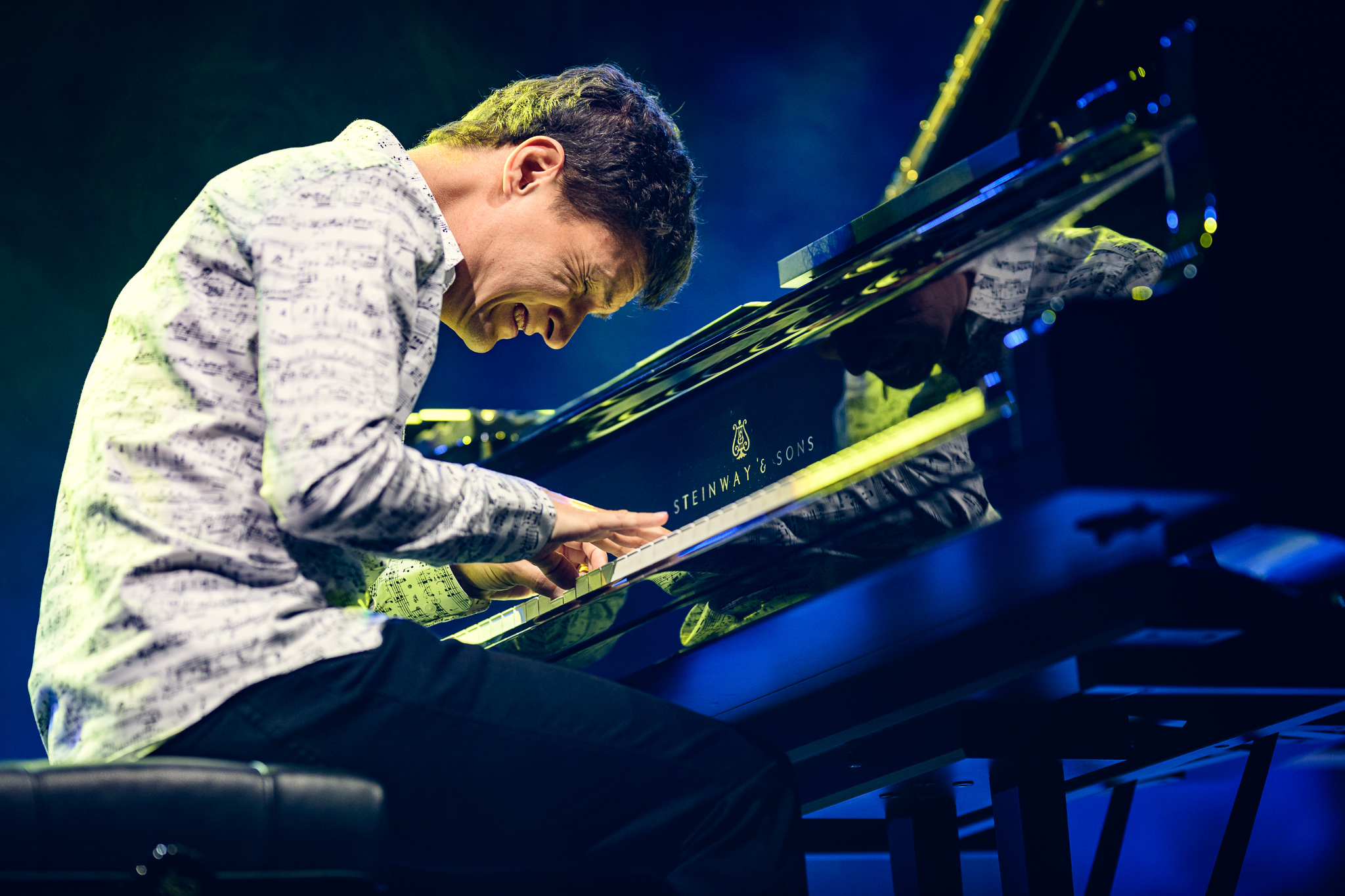 Mężczyzna w jasnej koszuli grający na fortepianie